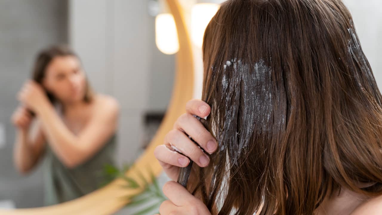 young women applying hair mask it helps to repair bleached damaged hair