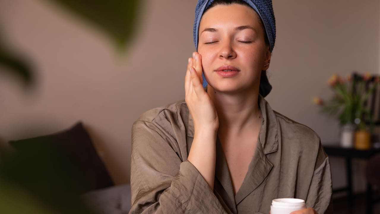 a women with beautiful skin applying cream on face