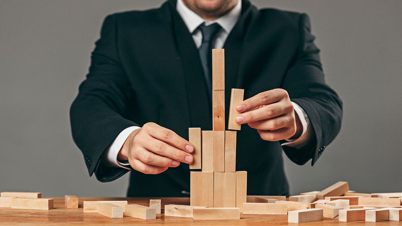 Man managing wooden cubes on the table depicting building blocks of emotional health