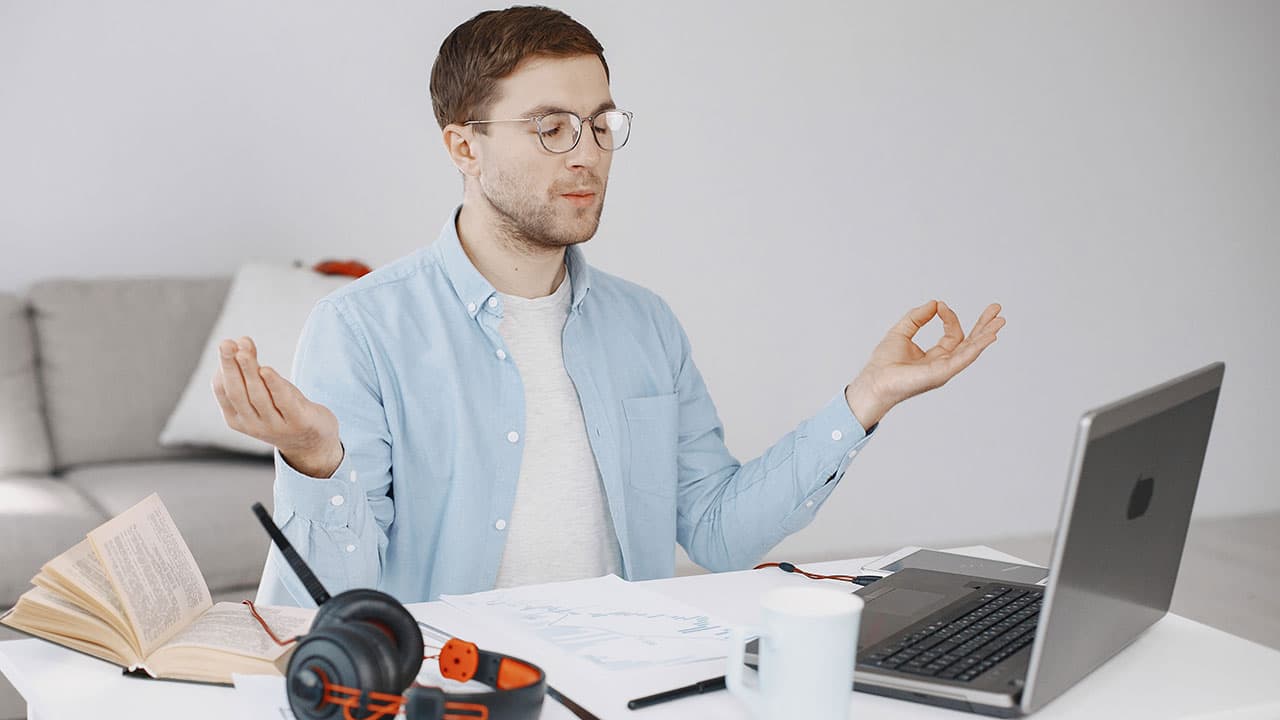 The Man sitting in the living room enjoying studying using a laptop, headset, and Meditation.