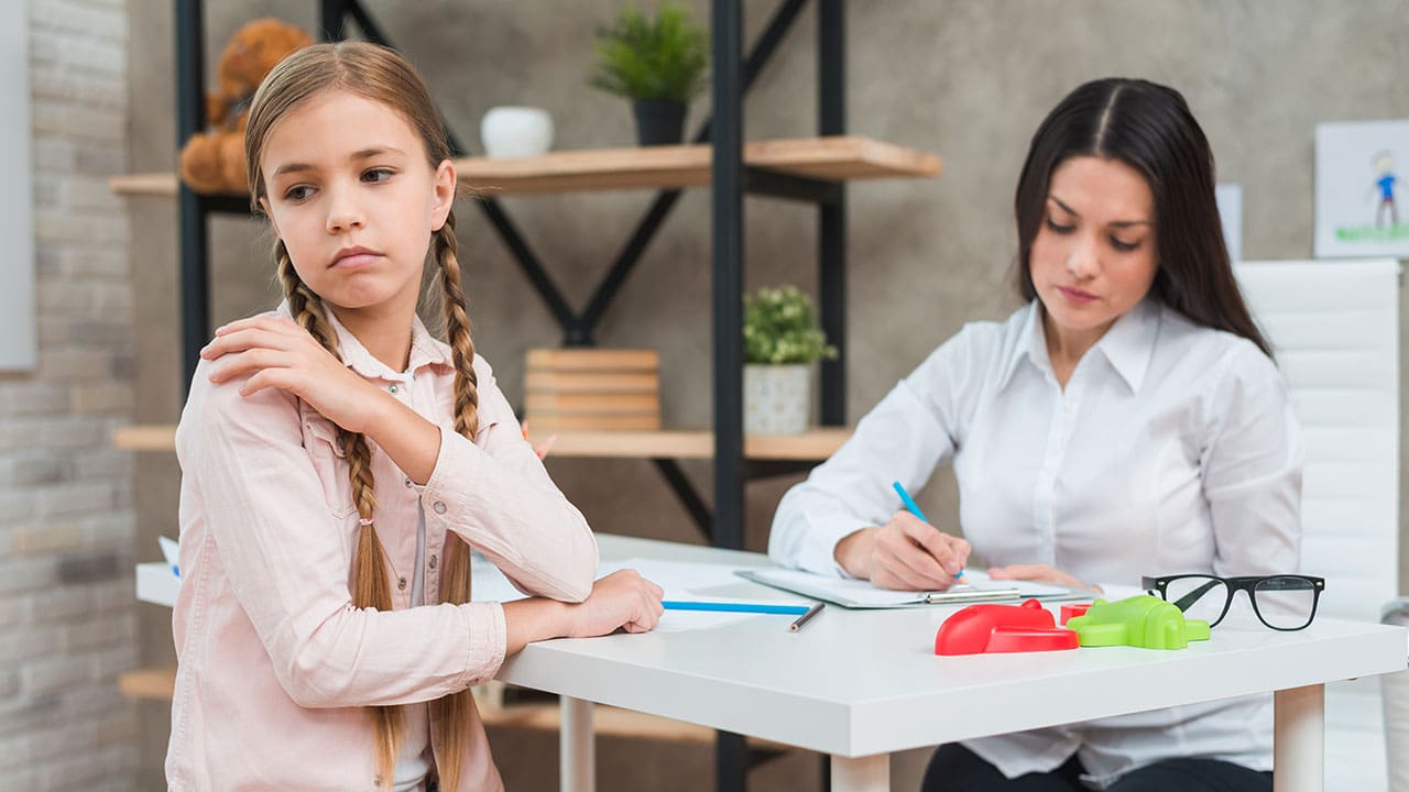 Psychologist writing notes during a meeting with a depressed girl