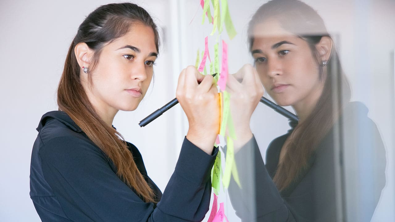 woman writing on a sticker with marker explaining emotional toughness