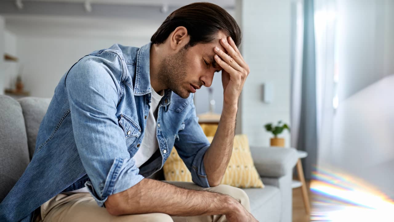 a young man holding his head