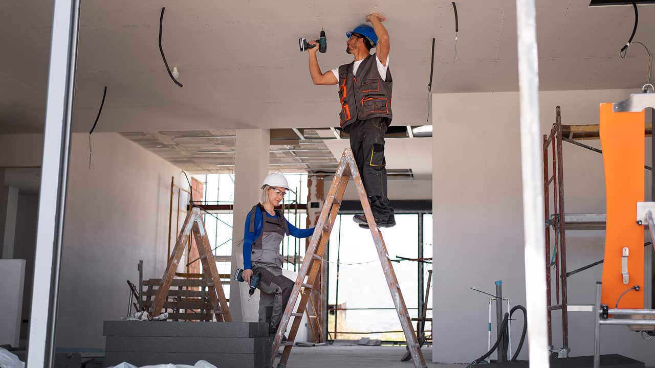 man and women standing on a ladder and doing some work